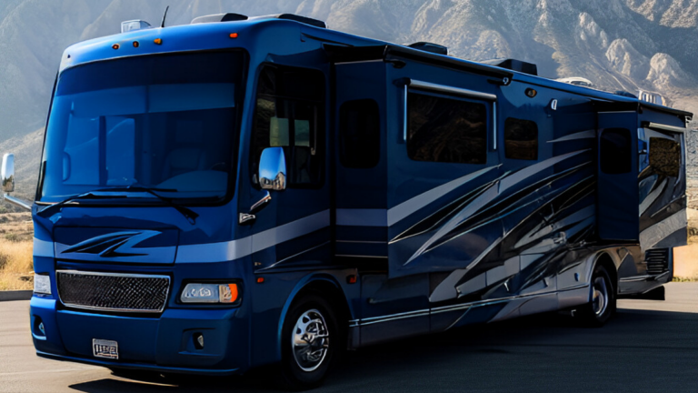A bold blue Class A motorhome with sleek silver and black graphics is parked against a rugged mountain backdrop, showcasing its spacious design and luxurious presence on the open road.