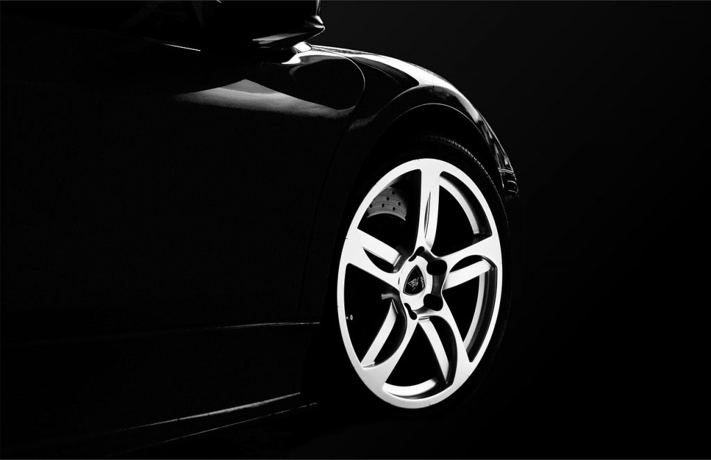 close-up shot of a sleek, high-performance sports car's front wheel and fender, captured with dramatic lighting.