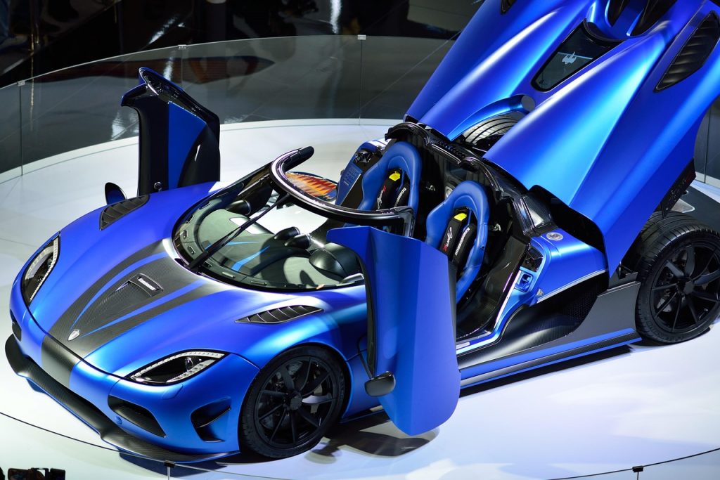 This electric blue Koenigsegg supercar, displayed with its dramatic dihedral doors open, is a perfect example of the kind of high-end vehicle that benefits from getting a supercar discount no one talks about.