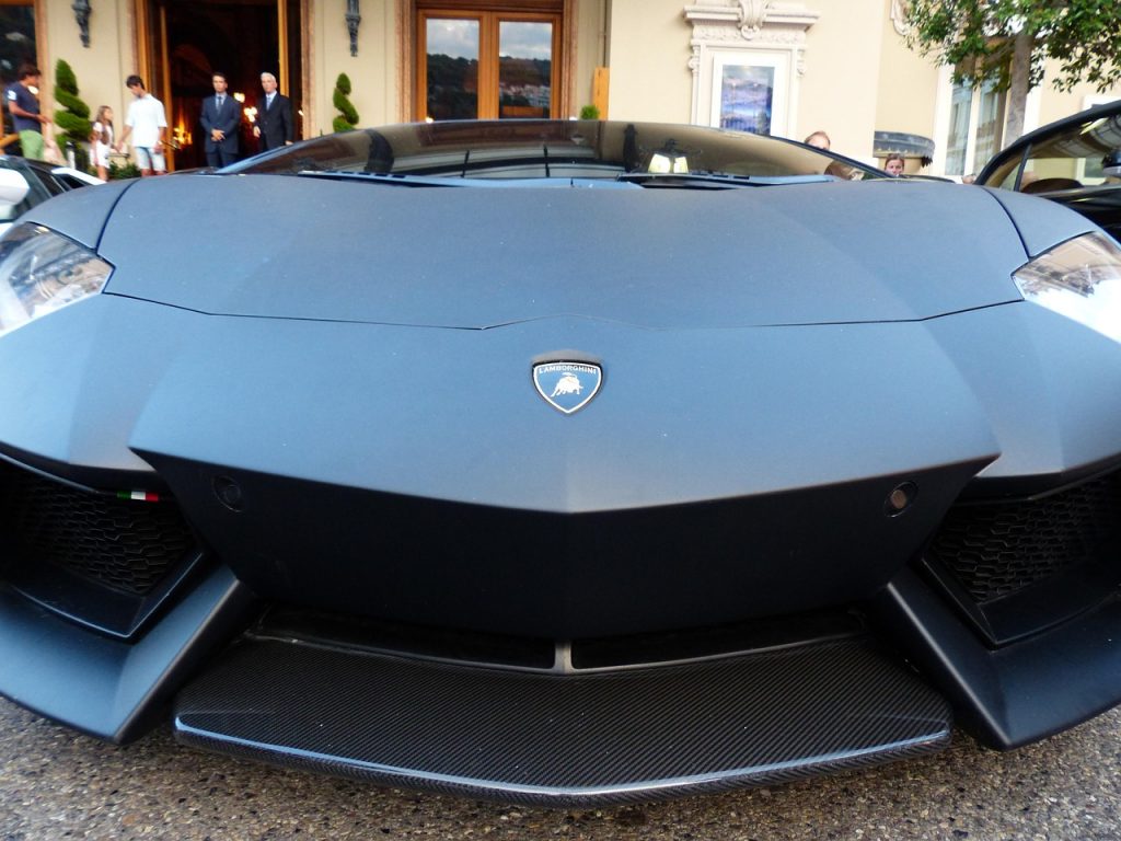This close-up of a matte black Lamborghini Aventador parked in front of a luxury venue showcases the kind of exotic car that highlights the value of Montana luxury tax savings for an exotic car purchase.