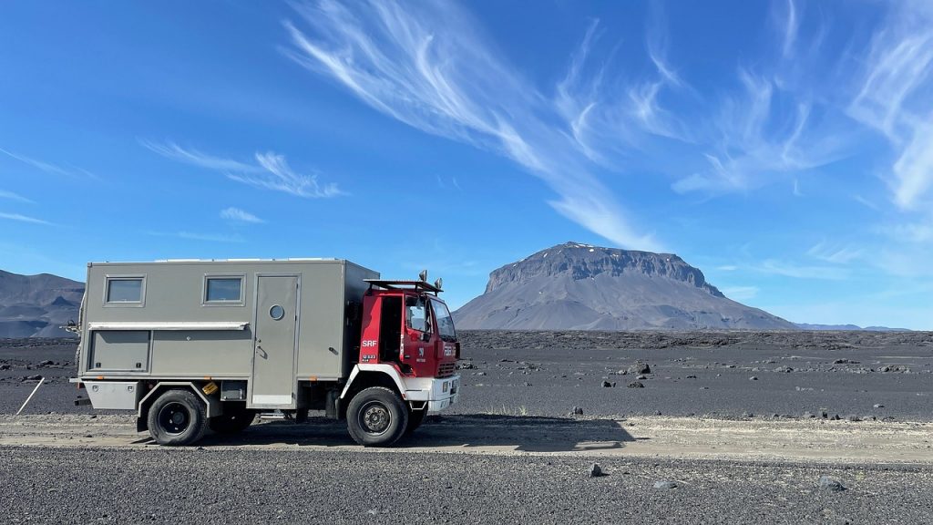 An expedition truck sits against a rugged mountain backdrop, ready for adventure and the tax savings that come with registering in Montana.