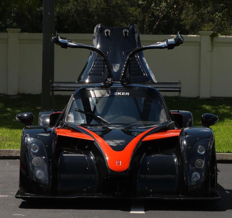 This is a black and orange Radical track car with its canopy-style cockpit open like butterfly wings.